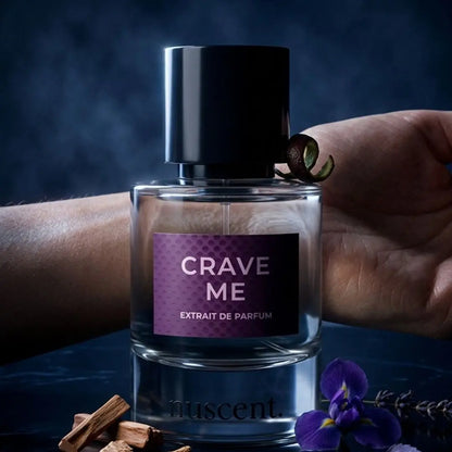 Hand holding and spraying Crave Me Extrait de Parfum fragrance with lavender and ginger ingredients visible