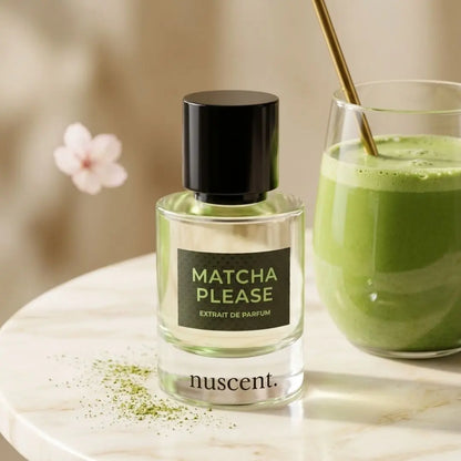 Matcha Please Extrait de Parfum fragrance displayed next to fresh matcha latte drink with white flowers and matcha powder on marble surface